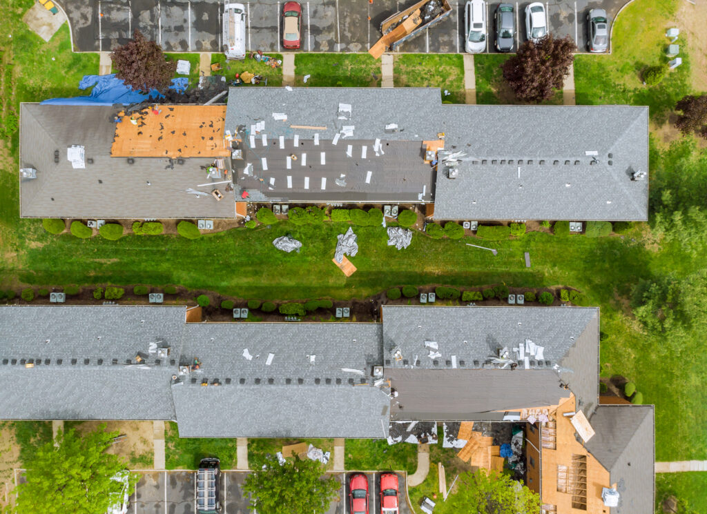 Aerial view of an apartment building’s roof installation, with tools and materials scattered around the site.