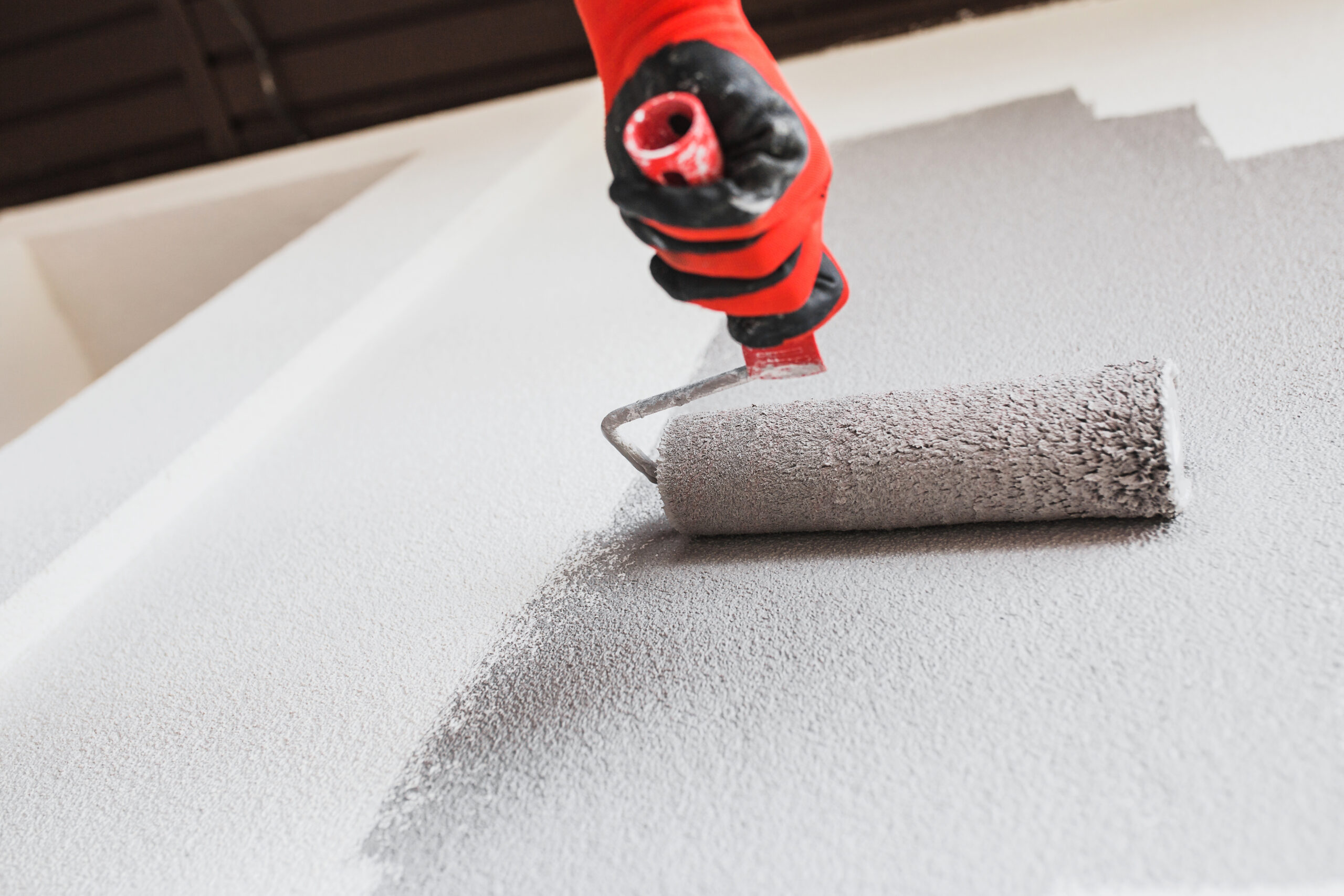 A professional commercial painter meticulously applies a fresh coat of paint to an interior room.