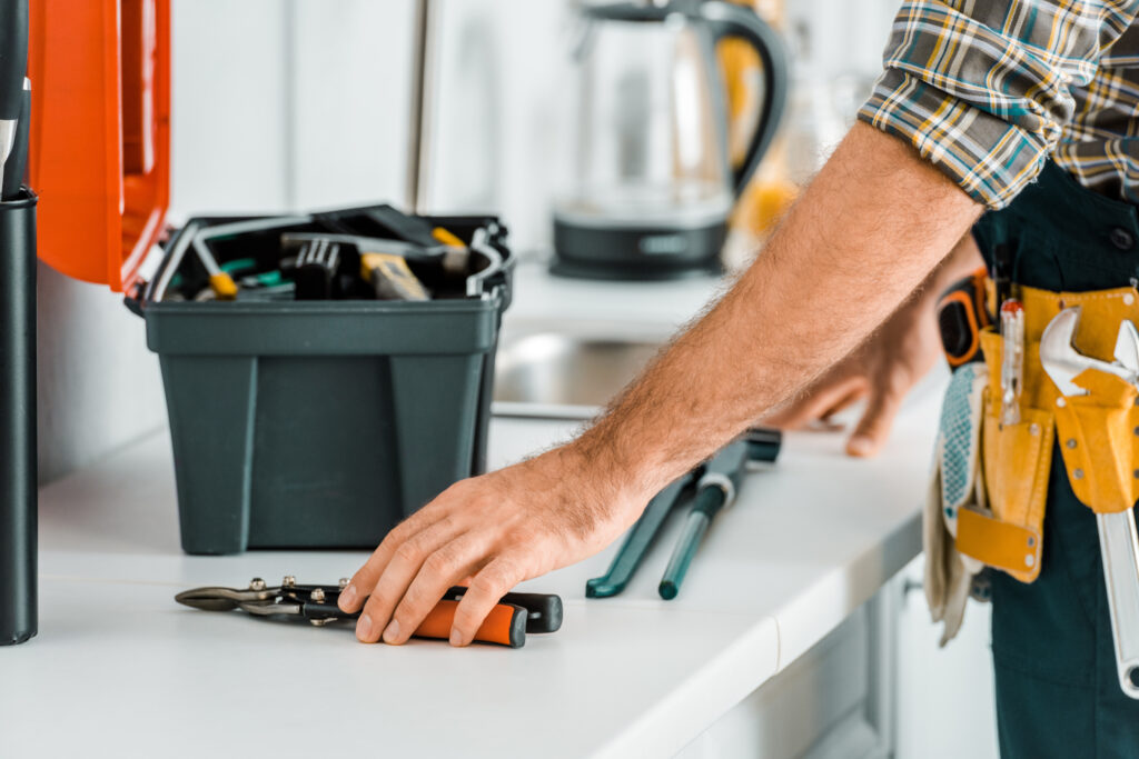 A repair worker places various tools on a kitchen counter to perform property maintenance.