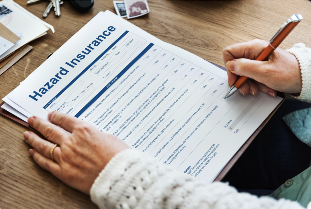Person filling out hazard insurance forms for property damage claims.